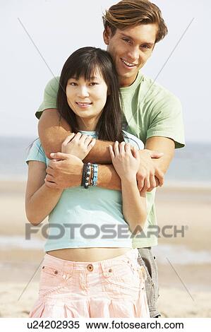 Stock Photography - Romantic Young Couple Embracing On Beach . Fotosearch