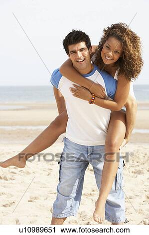 Romantic Young Couple Having Piggyback Fun On Beach View Large Photo Image Stock Image - Romantic Young Couple Having Piggyback Fun On Beach . Fotosearch