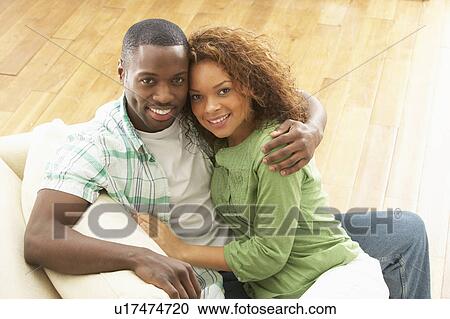 Stock Image - Romantic Young Couple Relaxing Sitting On Sofa. Fotosearch