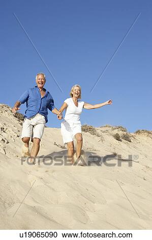Senior Couple Enjoying Beach Holiday Running Down Dune View Large Photo Image Stock Image - Senior Couple Enjoying Beach Holiday Running Down Dune. Fotosearch