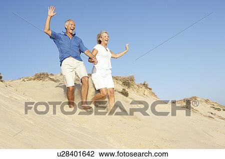 Senior Couple Enjoying Beach Holiday Running Down Dune View Large Photo Image Stock Image - Senior Couple Enjoying Beach Holiday Running Down Dune. Fotosearch