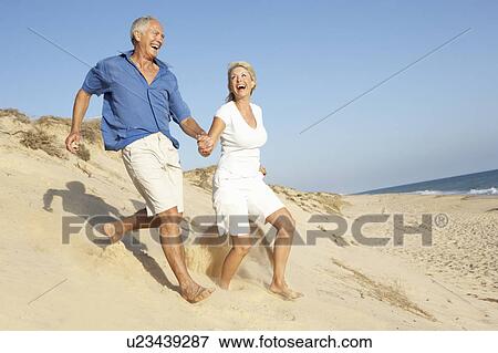 Senior Couple Enjoying Beach Holiday Running Down Dune View Large Photo Image Stock Photo - Senior Couple Enjoying Beach Holiday Running Down Dune. Fotosearch