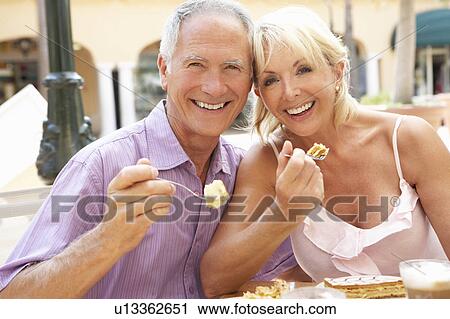 Stock Image - Senior Couple Enjoying Coffee And Cake In Café. Fotosearch