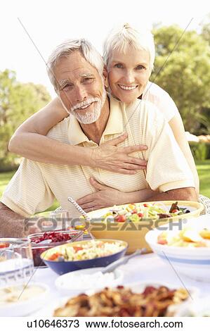 Stock Image - Senior Couple Enjoying Meal In Garden. Fotosearch