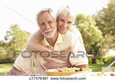 Stock Photo - Senior Couple Enjoying Meal In Garden. Fotosearch