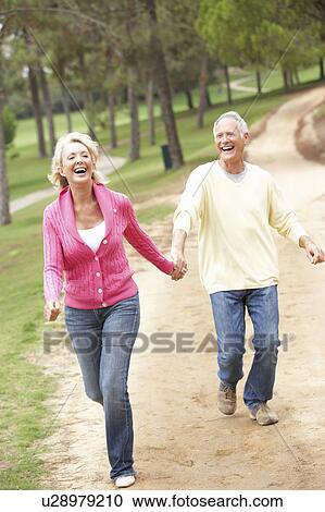 Stock Image - Senior Couple enjoying walk in park. Fotosearch