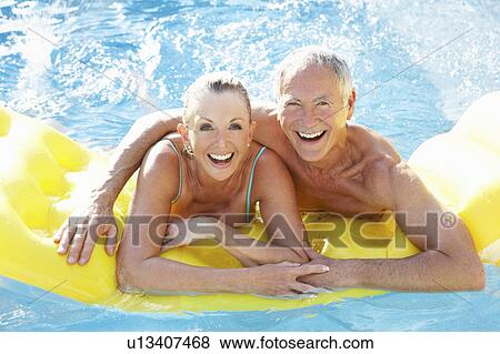 Stock Photo - Senior couple having fun in pool. Fotosearch