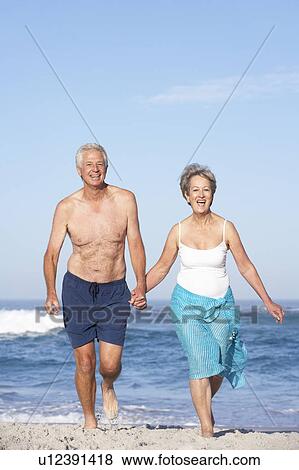 Senior Couple On Holiday Running Along Sandy Beach View Large Photo Image Stock Photo - Senior Couple On Holiday Running Along Sandy Beach. Fotosearch