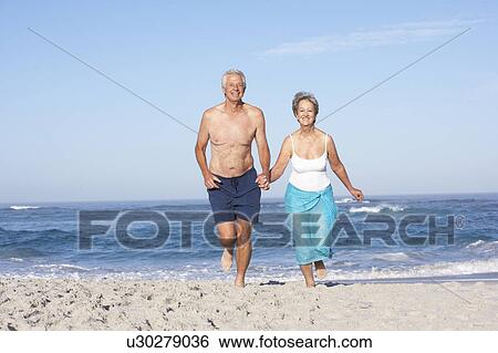 Senior Couple On Holiday Running Along Sandy Beach View Large Photo Image Stock Photograph - Senior Couple On Holiday Running Along Sandy Beach. Fotosearch