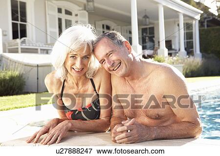 Stock Photo - Senior Couple Relaxing by Outdoor Pool. Fotosearch
