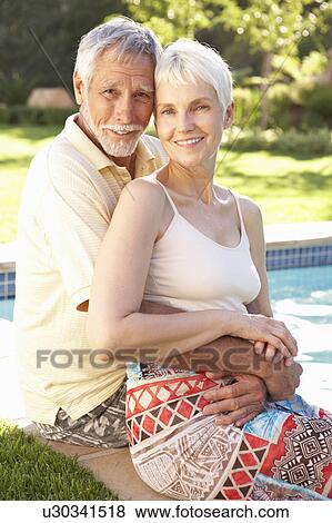 Senior Couple Relaxing By Pool In Garden View Large Photo Image Stock Photo - Senior Couple Relaxing By Pool In Garden. Fotosearch