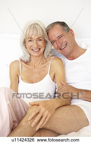 Stock Photograph - Senior Couple Relaxing On Bed. Fotosearch