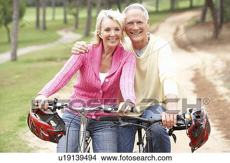 Senior couple riding bicycle in park View Large Photo Image Picture - Senior couple riding bicycle in park. Fotosearch