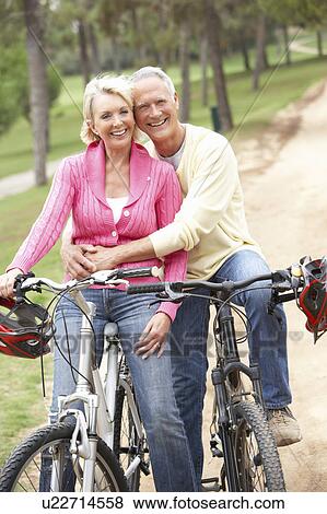 Stock Photo - Senior couple riding bicycle in park. Fotosearch