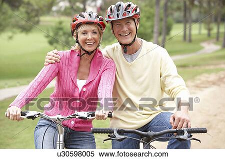 Senior couple riding bicycle in park View Large Photo Image Stock Photography - Senior couple riding bicycle in park. Fotosearch