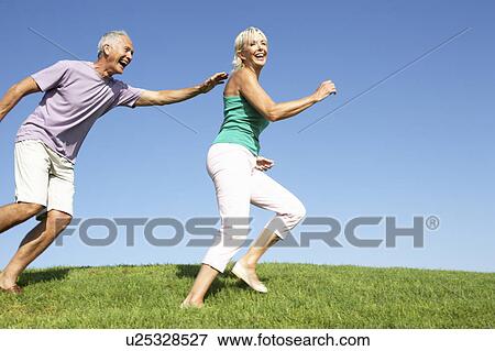 Senior couple running though field View Large Photo Image Stock Photo - Senior couple running though field. Fotosearch