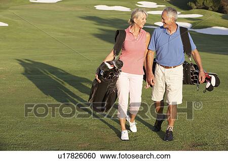Senior Couple Walking Along Golf Course Carrying Bags View Large Photo Image Stock Image - Senior Couple Walking Along Golf Course Carrying Bags. Fotosearch