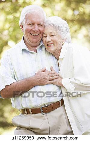 Stock Image - Senior Couple Walking In Park. Fotosearch
