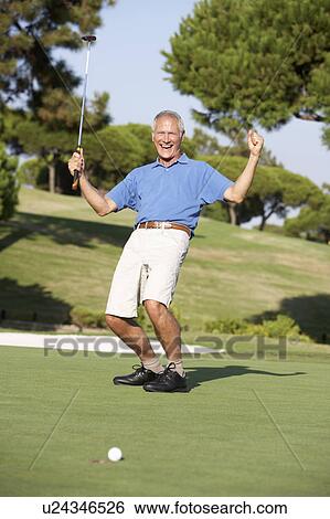 Stock Photograph - Senior Male Golfer On Golf Course Putting On Green. Fotosearch