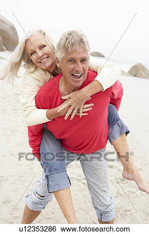 Senior Man Giving Woman Piggyback On Winter Beach View Large Photo Image Stock Photograph - Senior Man Giving Woman Piggyback On Winter Beach. Fotosearch