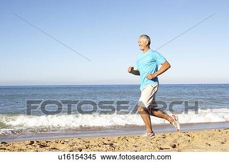 Stock Photography - Senior Man In Fitness Clothing Running Along Beach. Fotosearch