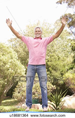 Picture - Senior Man Jumping On Trampoline In Garden. Fotosearch