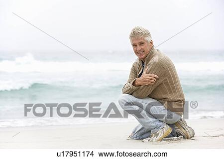 Senior Man On Holiday Kneeling On Winter Beach View Large Photo Image Picture - Senior Man On Holiday Kneeling On Winter Beach. Fotosearch
