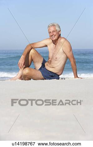 Stock Photo - Senior Man On Holiday Sitting On Sandy Beach. Fotosearch