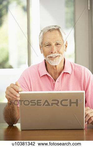 Stock Image - Senior Man Using Laptop At Home. Fotosearch