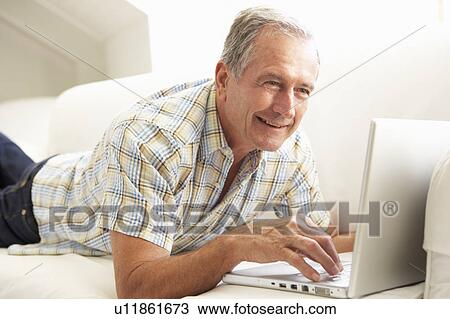 Senior Man Using Laptop Relaxing Sitting On Sofa At Home View Large Photo Image Stock Image - Senior Man Using Laptop Relaxing Sitting On Sofa At Home. Fotosearch