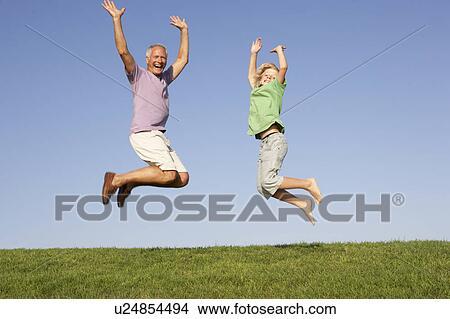 Picture - Senior man with grandson jumping in air. Fotosearch