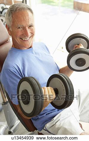 Stock Photo - Senior Man Working With Weights In Gym. Fotosearch