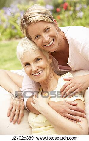 Stock Photo - Senior Woman And Adult Daughter Relaxing In Garden. Fotosearch