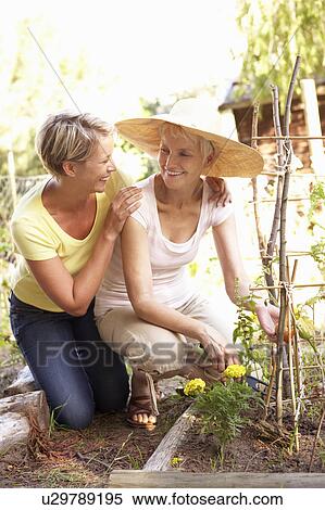 Stock Photography - Senior Woman And Adult Daughter Relaxing In Garden. Fotosearch