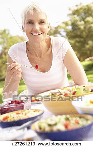 Stock Photo - Senior Woman Enjoying Meal In Garden. Fotosearch
