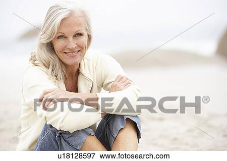 Stock Photo - Senior Woman On Holiday Sitting On Winter Beach. Fotosearch
