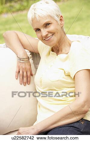 Stock Image - Senior Woman Relaxing In Garden. Fotosearch