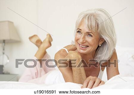 Stock Image - Senior Woman Relaxing On Bed. Fotosearch