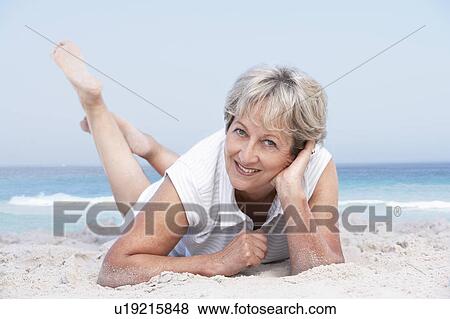 Stock Photo - Senior Woman Relaxing On Sandy Beach. Fotosearch