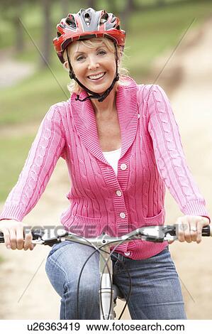 Stock Photo - Senior woman riding bicycle in park. Fotosearch