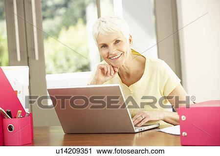 Stock Image - Senior Woman Using Laptop At Home. Fotosearch
