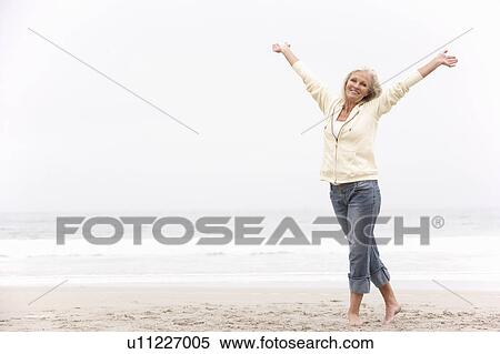 Senior Woman With Arms Outstretched On Winter Beach View Large Photo Image Stock Photography - Senior Woman With Arms Outstretched On Winter Beach. Fotosearch