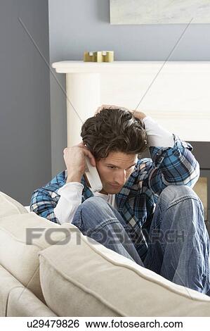 Stressed Man Sitting On Sofa At Home Talking On Phone View Large Photo Image Stock Photograph - Stressed Man Sitting On Sofa At Home Talking On Phone. Fotosearch