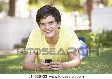 Teenage Boy Laying In Park Using Mobile Phone View Large Photo Image Stock Image - Teenage Boy Laying In Park Using Mobile Phone. Fotosearch