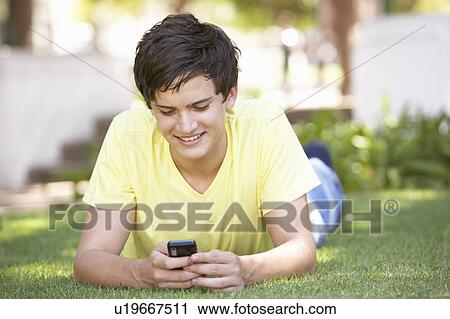 Teenage Boy Laying In Park Using Mobile Phone View Large Photo Image Stock Image - Teenage Boy Laying In Park Using Mobile Phone. Fotosearch