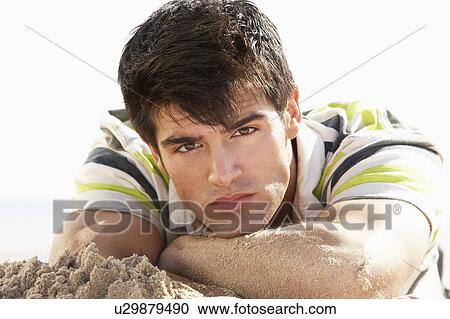Stock Image - Teenage Boy Sitting On Beach. Fotosearch