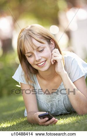 Teenage Girl Laying In Park Using Mobile Phone View Large Photo Image Picture - Teenage Girl Laying In Park Using Mobile Phone. Fotosearch