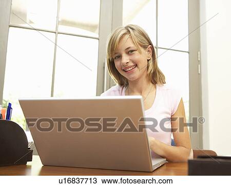 Stock Image - Teenage Girl Using Laptop At Home. Fotosearch