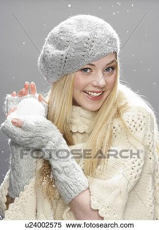 Stock Photography - Teenage Girl Wearing Warm Winter Clothes And Hat Holding Snowball In Studio. Fotosearch