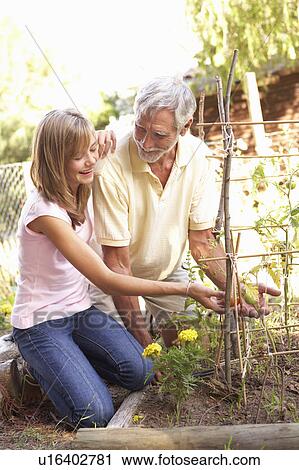 Stock Image - Teenage Granddaughter And Grandfather Relaxing In Garden. Fotosearch